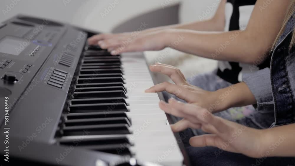Girl's hands on the keyboard of the piano. The girl plays piano,close up piano. Hands on the white keys of the Piano Playing a Melody. Women's Hands on the keyboard, Playing the Notes Melody. Girl's hands on the keyboard of the piano. The girl plays piano,close up piano. Hands on the white keys of the Piano Playing a Melody. Women's Hands on the keyboard, Playing the Notes Melody.