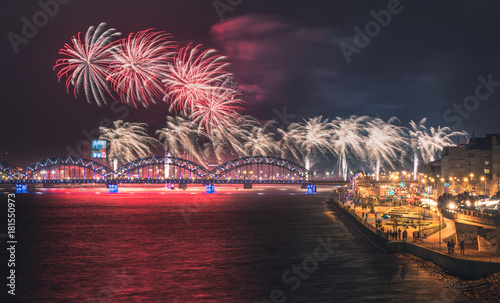 Colorful fireworks in Riga city with panoramic view over the river Daugava and railroad bridge. New year celebration. 