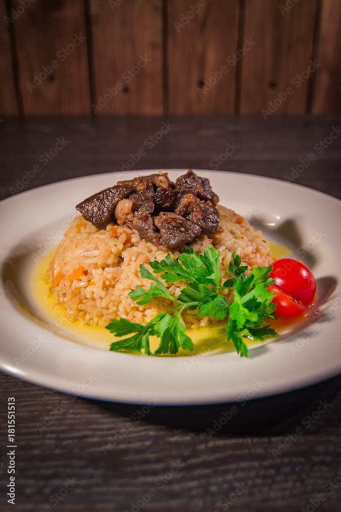 A tasty dish of rice on a plate. On a wooden background A tasty dish of rice on a plate. On a wooden background