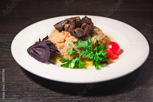 A tasty dish of rice on a plate. On a wooden background