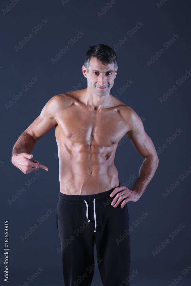 muscular man. Muscular man on a grey background showing muscles. Fitness instructor. Fitness professional. Workout. Men's fitness. muscular man. Muscular man on a grey background showing muscles. Fitness instructor. Fitness professional. Workout. Men's fitness.