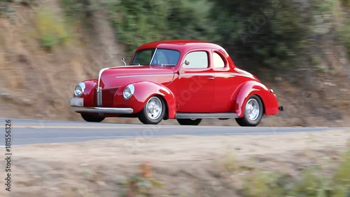 Red classic car drives on highway, rack focus