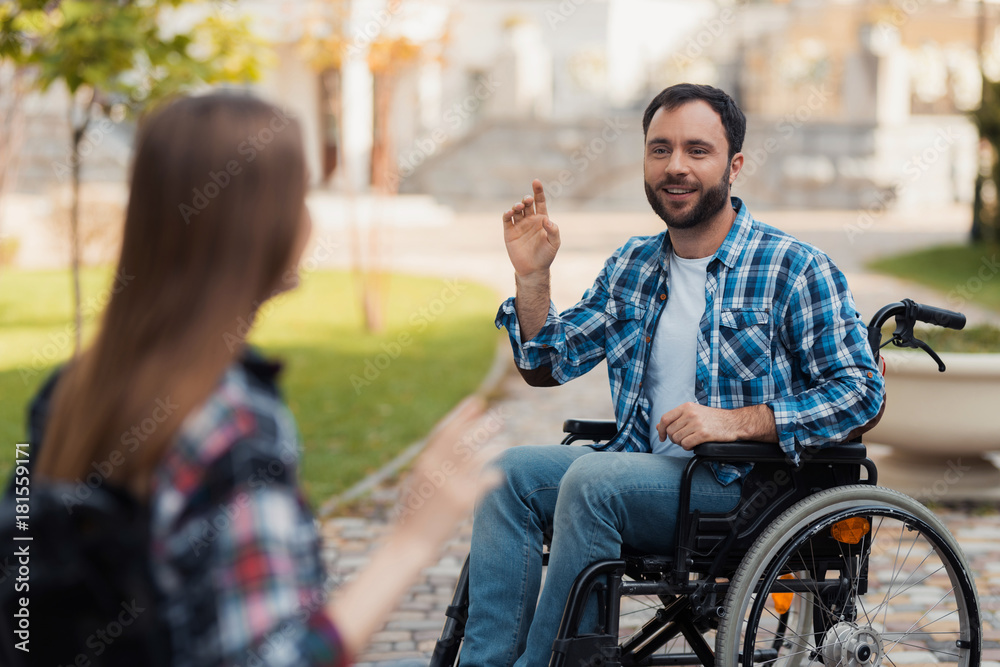 A couple of invalids on wheelchairs met in the park. A man is greeting a woman. A couple of invalids on wheelchairs met in the park. A man is greeting a woman.