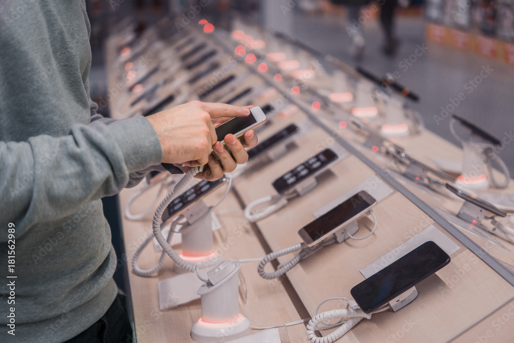 Closeup view of male customer hands, choosing smartphone in the mobile phone shop. difficult decision. Various choice. Toned