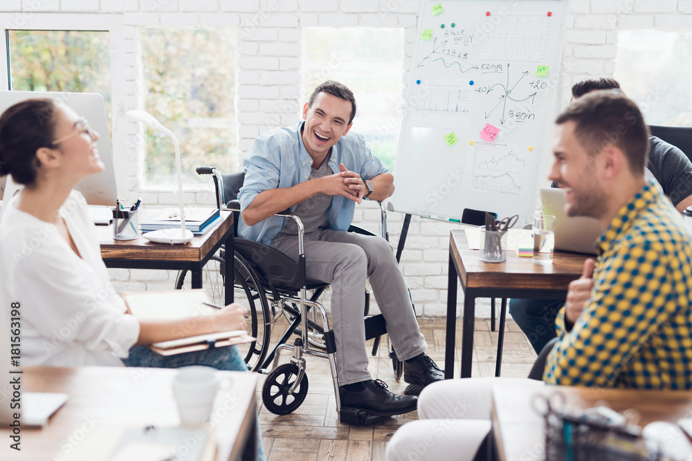 Office workers and man in a wheelchair discussing business moments in a modern office.