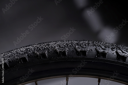 Black bike tire with water drops on abstract background. © eshma