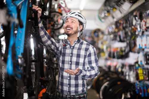 friendly man in helmet chooses for himself sports bike in bicycle shop © JackF