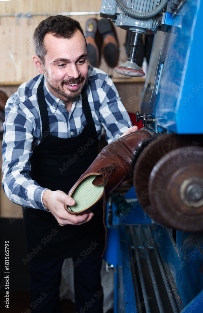 male worker fixing failed shoes in shoe repair workshop