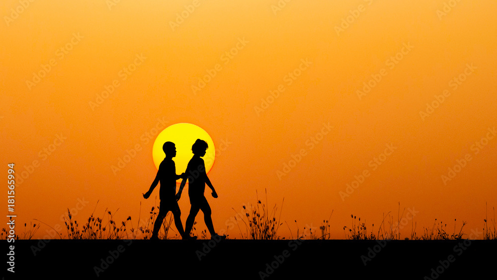 Silhouette boy and girl walking together at sunset