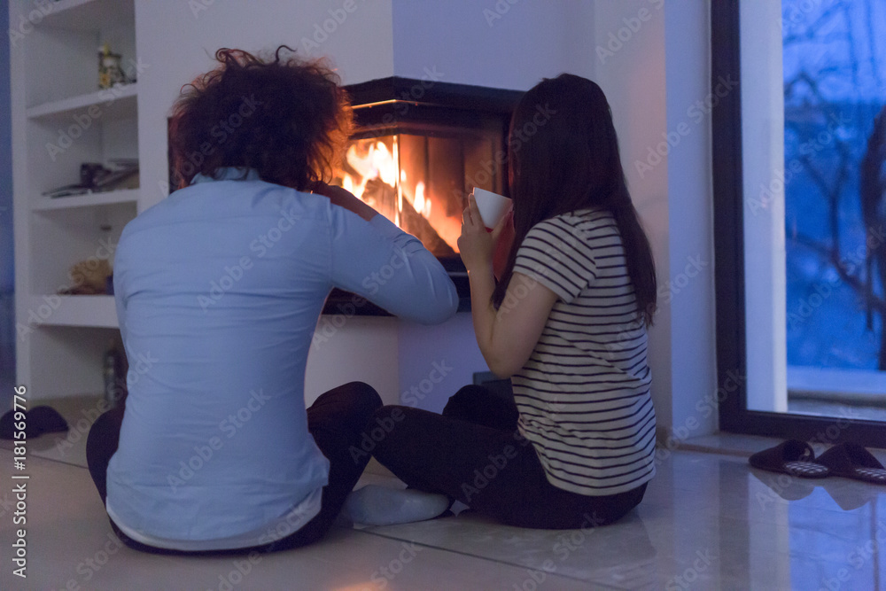 happy multiethnic couple sitting in front of fireplace