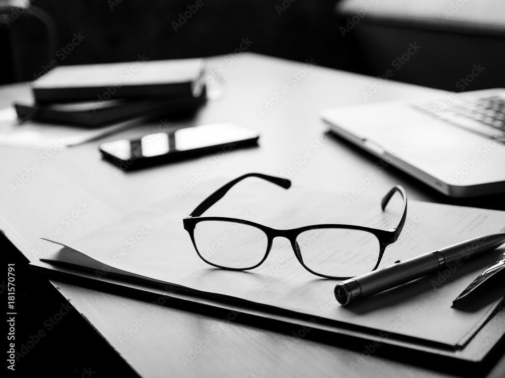 Fototapeta premium Office desk with glasses, documents,laptop,smart phone and notebook. Black and White tone