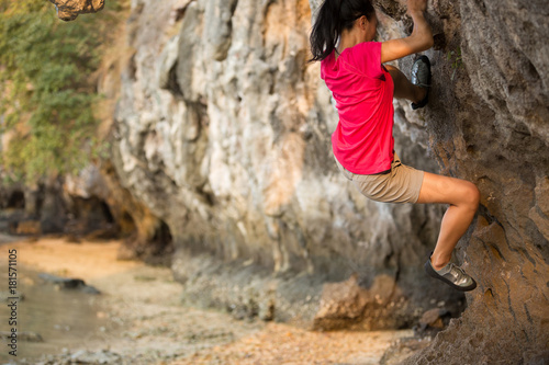  Young woman rock climber climbing on seaside cliff
