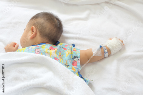 Hands of a little Boy attaching intravenous tube to patient's hand in hospital bed.
