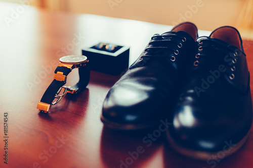 Set of groom cufflinks in a box, classic leather shoes, expensive watches, mens accessories of a businessman on a wooden table. closeup. Vintage tonted photo. photo