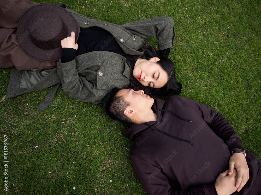 High angle view of couple of Chinese young people lying on green grass field and looking each other full of love, lover concept. High angle view of couple of Chinese young people lying on green grass field and looking each other full of love, lover concept.