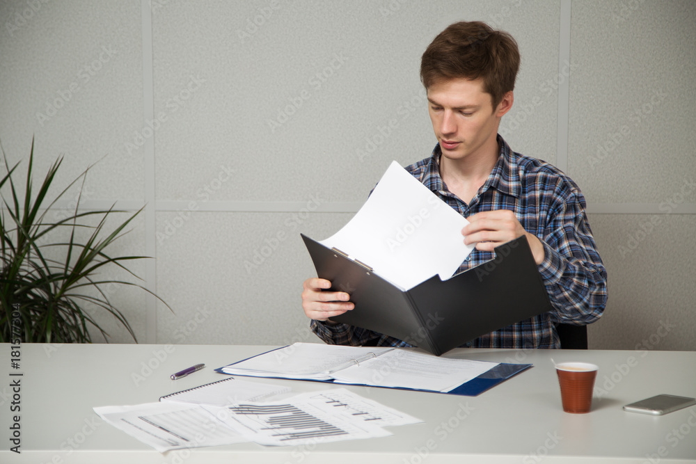 entrepreneur in casual clothes sitting at a table, studying documents entrepreneur in casual clothes sitting at a table, studying documents