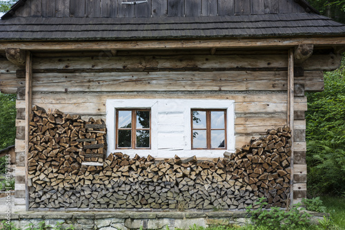 An old wooden building with windows and stacked wood.