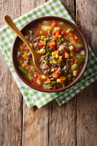 Vegetable soup with ground beef close-up in a bowl. Vertical top view