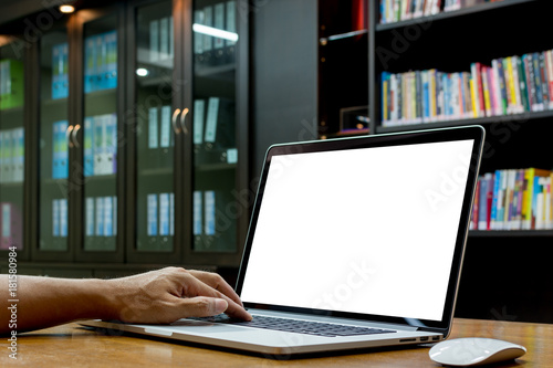 Hand of man using laptop in libray with book shelf in background, blank screen laptop. selective focus.