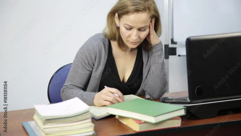 female student reads and makes notes in a book in front of laptop female student reads and makes notes in a book in front of laptop