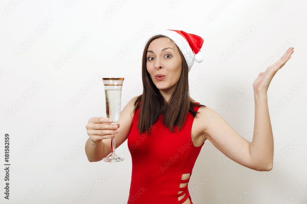 Beautiful caucasian young happy woman with charming smile in red dress and Christmas hat standing with glass of champagne on white background. Santa girl isolated. New Year 2018 holiday concept Beautiful caucasian young happy woman with charming smile in red dress and Christmas hat standing with glass of champagne on white background. Santa girl isolated. New Year 2018 holiday concept
