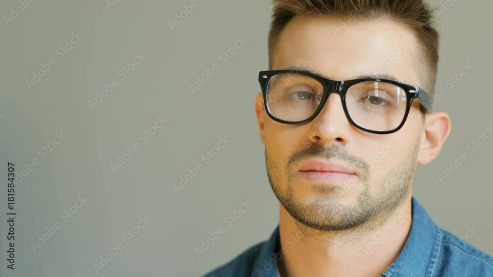 Closeup. A portrait of a handsome young man looking seriously into the camera. Wall in the background. Blurred background. Closeup. A portrait of a handsome young man looking seriously into the camera. Wall in the background. Blurred background.