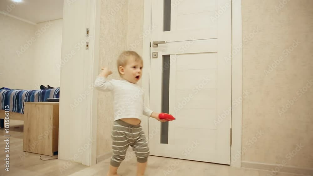 Little boy in pajamas while at home playing hide and seek with the door. Opens and closes the door to the room. Close-up.