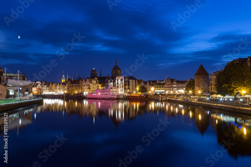 Scenic view of the Motlawa River and lit old buildings on the Long Bridge waterfront at the Main Town (Old Town) in Gdansk, Poland, in the evening. Copy space.