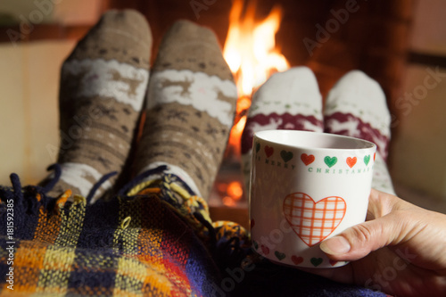 A man and a woman in front of a fireplace in warm socks.