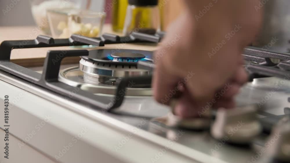 Advanced gas stove with automatic electric ignition. Chef turns the knob top valvet on and puts on wok to prepare healthy and tasty dish.