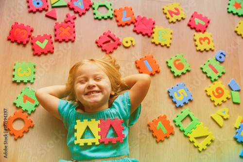 happy little girl learn numbers and shapes, play with puzzle