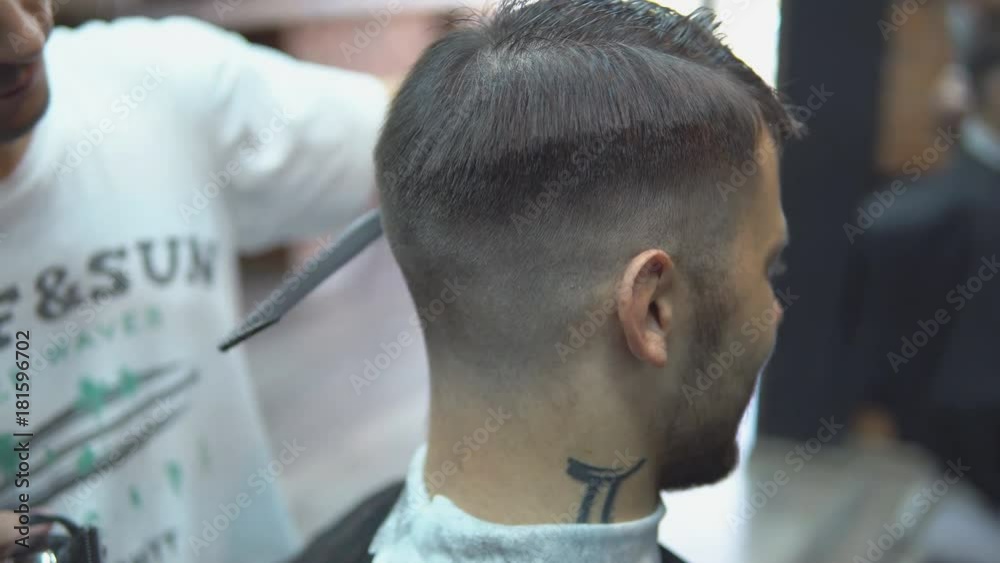 Master cuts hair and beard of men in the barbershop, hairdresser makes hairstyle for a young man. Master cuts hair and beard of men in the barbershop, hairdresser makes hairstyle for a young man.