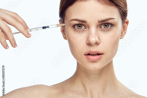 Beautiful young woman on white isolated background holds a syringe, plastic, medicine