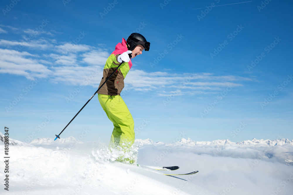Young, sexy woman is skiing in winter paradise in the alps with a beautiful blue sky and wonderful white snowy mountains 