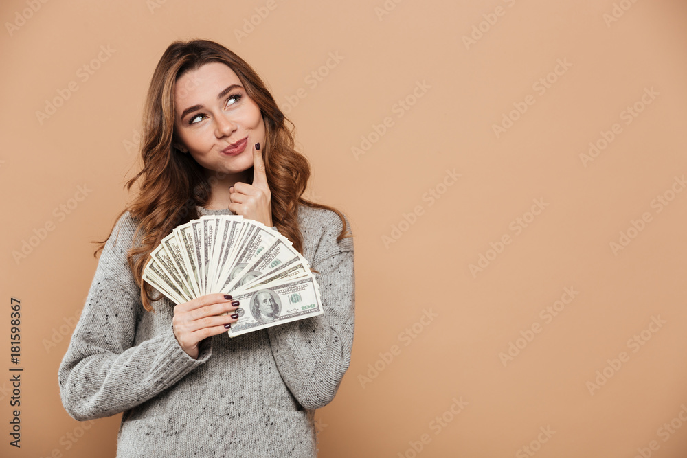 Obraz premium Close-up portrait of playful beautiful woman in gray woolen sweater holding bumch of money, looking aside