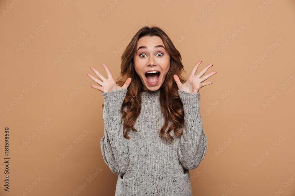 Pretty emotional girl in woolen jersey standing with opened palms, looking at camera Pretty emotional girl in woolen jersey standing with opened palms, looking at camera