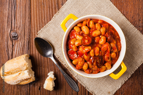 Baked beans in tomato sauce served in yellow, clay bowls.