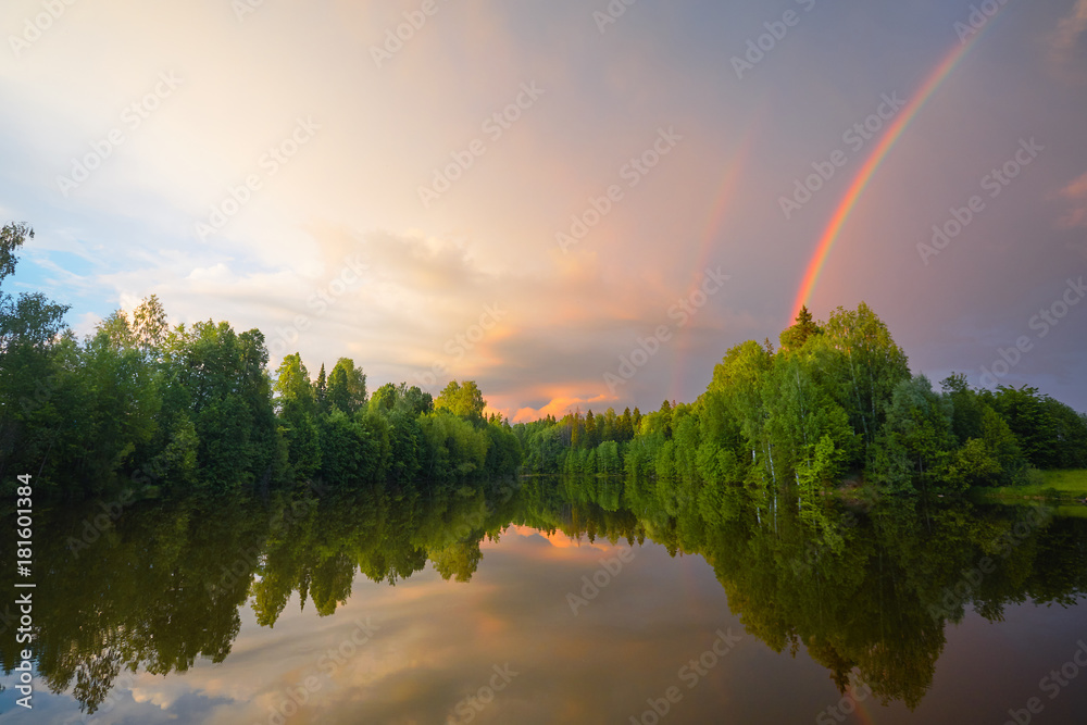Rainbow over calm water of a forest lake. Beautiful clouds in the evening sky. Rainbow over calm water of a forest lake. Beautiful clouds in the evening sky.