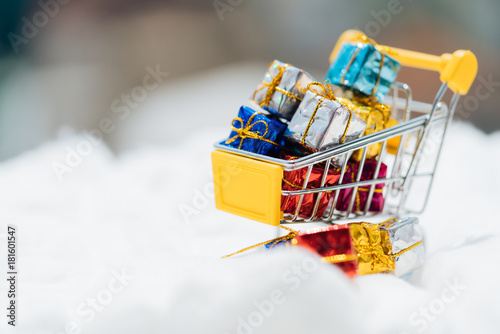 Miniature people: small gift on shopping cart with white snow. Christmas Holiday decorative concept. photo