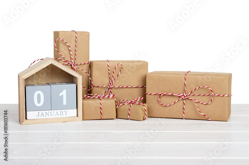 Gift box wrapped in recycled paper with ribbon bow and calendar 1january on wooden table. Isolated photo