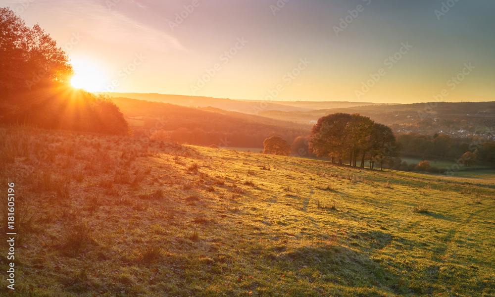 Red, Orange and yellow glow of a sunset over green pastures and trees in the English Countryside. Gibside near Newcastle upon Tyne.