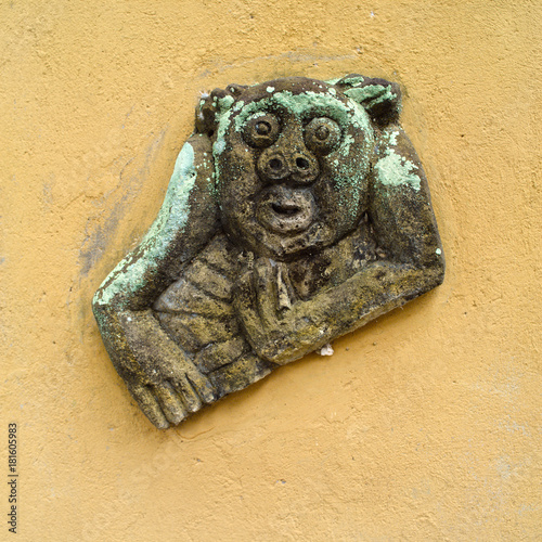 wall statue of grinning monkey which is carved from the stone in the Ubud monkey forest, Bali, Indonesia