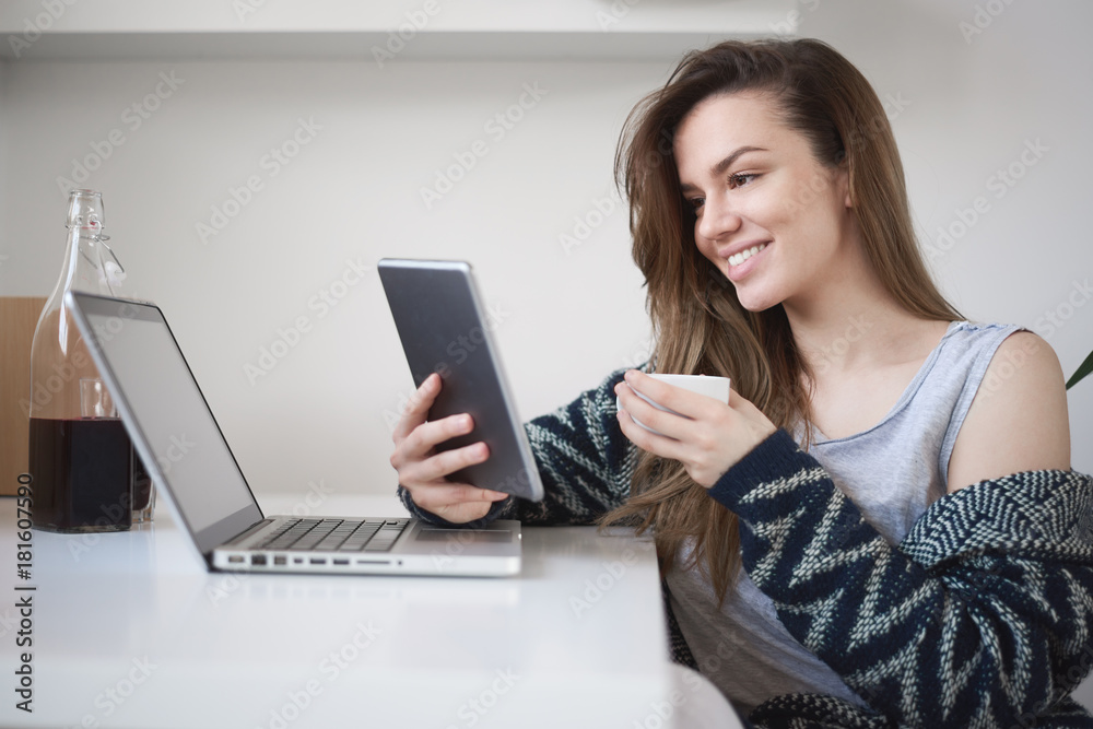 Young woman using tablet and drinking coffee while sitting in study room in the morning Young woman using tablet and drinking coffee while sitting in study room in the morning