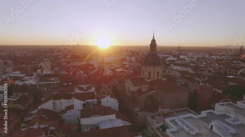 Aerial drone footage from drone that flies around spire of old ancient cathderal in middle of historical centre of Madrid, Spain. European touristic destination at summer sunset photo