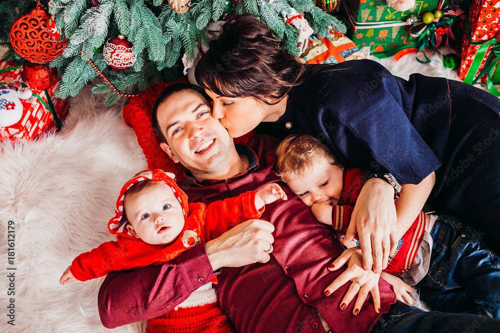 Parents and their two sons lie under Christmas tree Parents and their two sons lie under Christmas tree