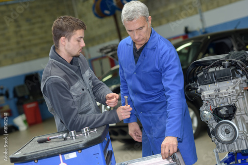 mechanic helping apprentice to fix engine