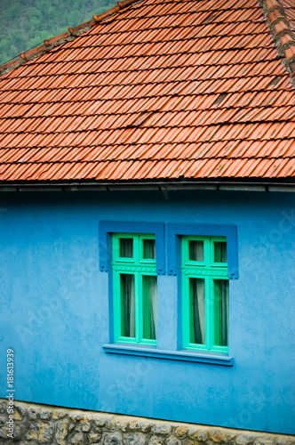 country side house vivid bright blue color wall with two green windows and roof, country side house 