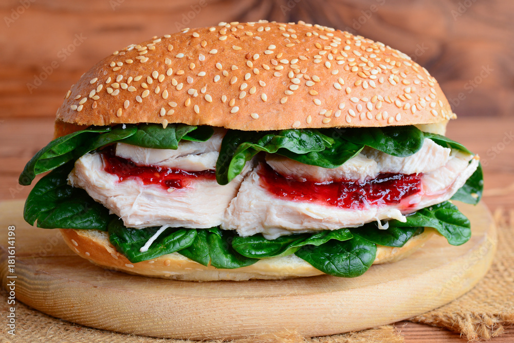 Healthy chicken burger. Homemade chicken burger with spinach and jam on a wooden board. Closeup Healthy chicken burger. Homemade chicken burger with spinach and jam on a wooden board. Closeup