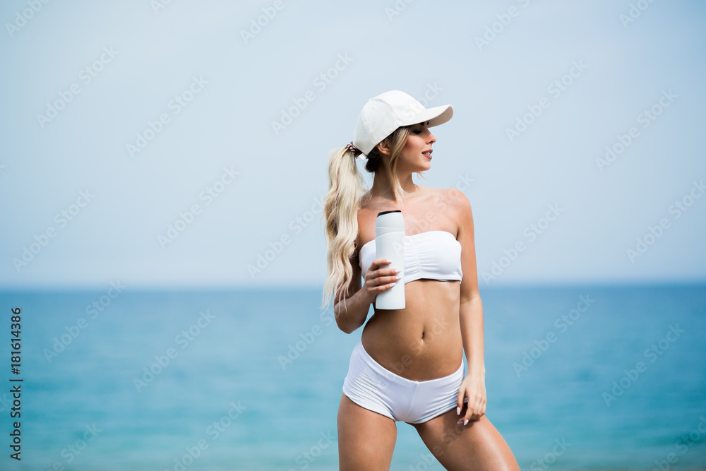young beautiful sports girl posing with a bottle in his hand on the beach young beautiful sports girl posing with a bottle in his hand on the beach