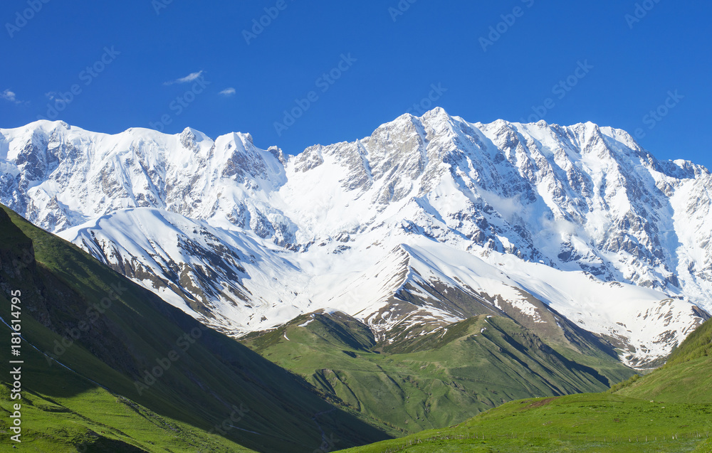 glacier and green hills in Georgia under blue sky
